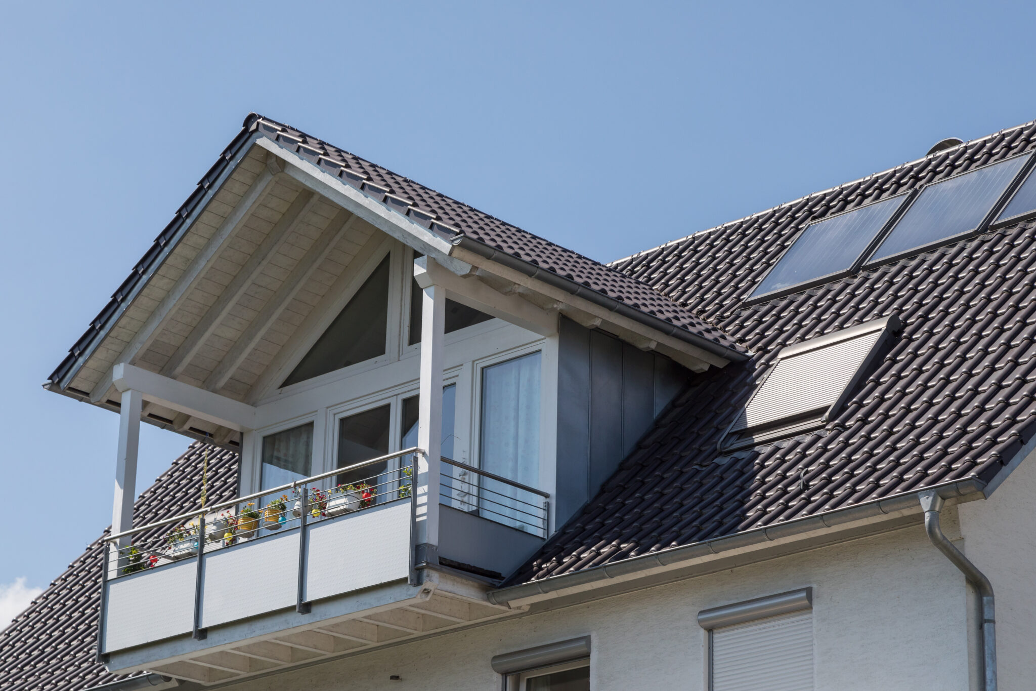 Kosten für eine Dachgaube. Ein graues Haus mit einer grauen Dachgaube